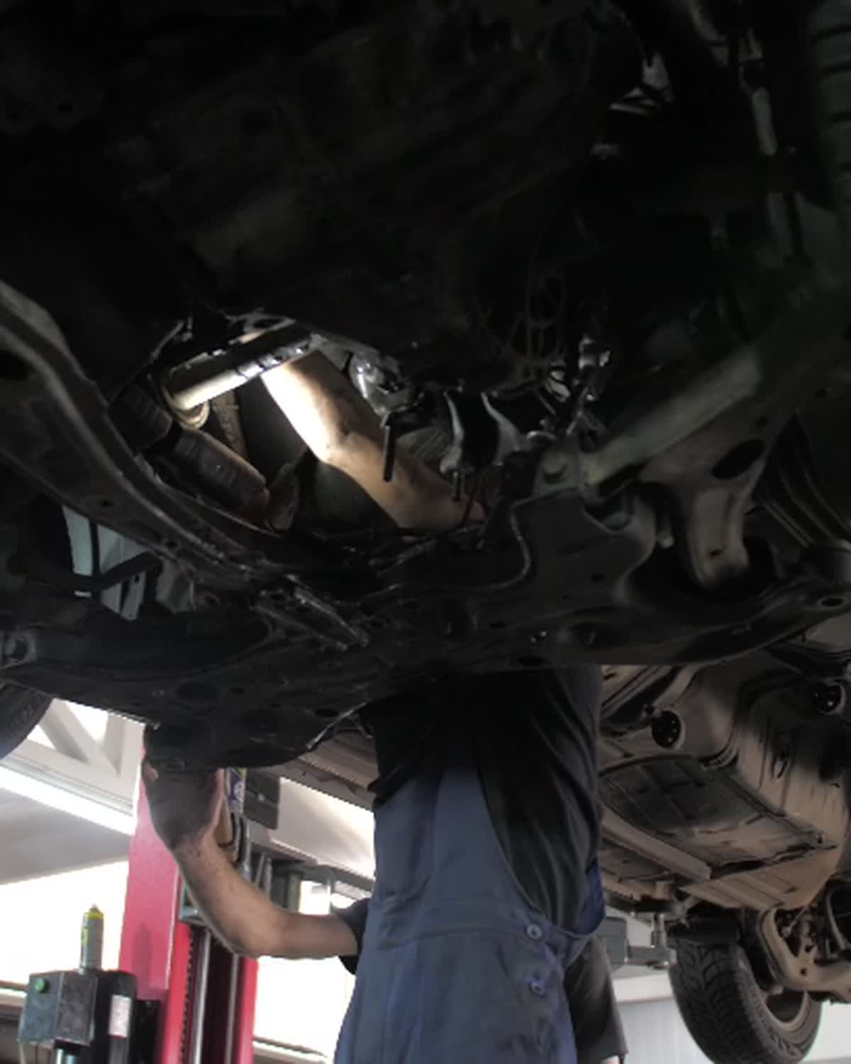Mechanic inspecting the vehicle gearbox and transmission from underneath
