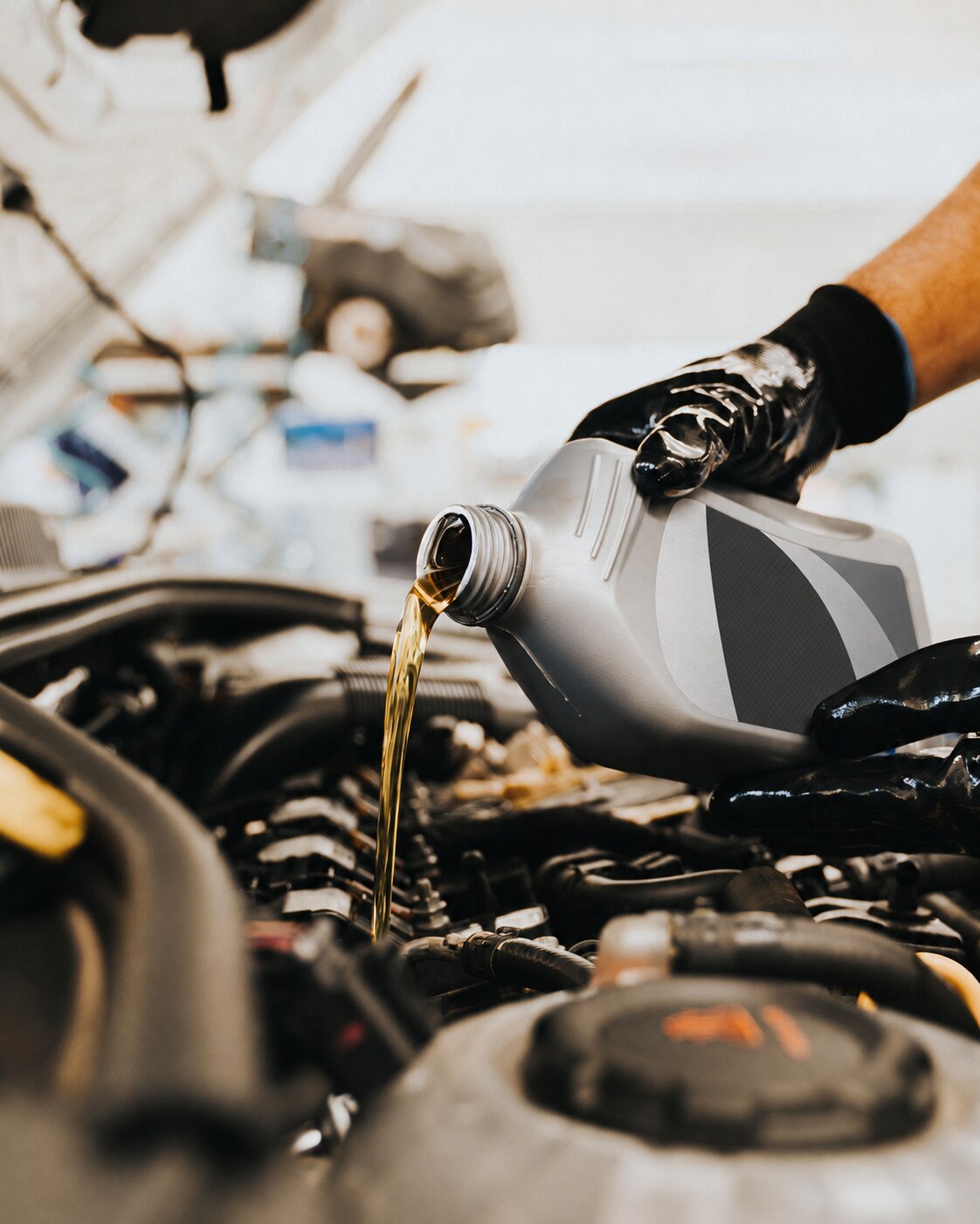 Mechanic pouring automotive fluid from an unbranded bottle