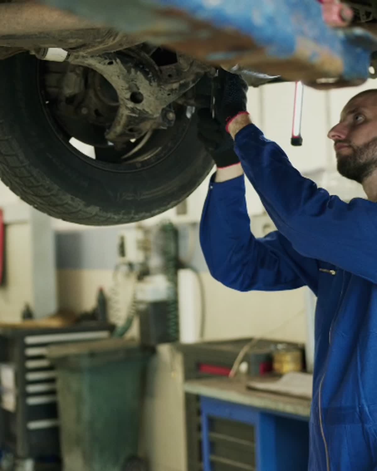 Mechanic inspecting suspension components beneath a raised vehicle